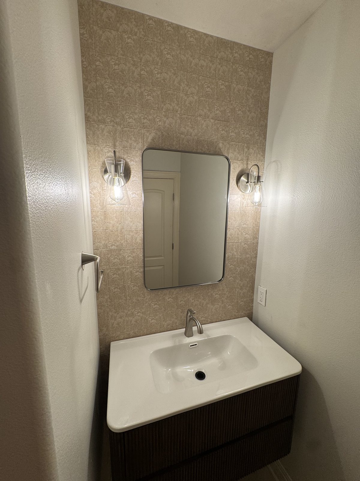 Paired vanity sconces and mirror in a finished powder bath.